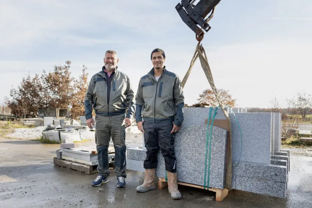 Deux marbriers de Florian Leclerc posant à côté d’un chargement de stèles en granit.