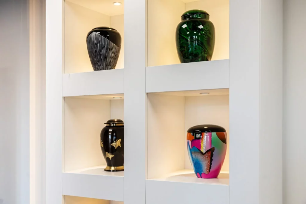 Urnes funéraires modernes exposées dans une vitrine lumineuse de l'agence.